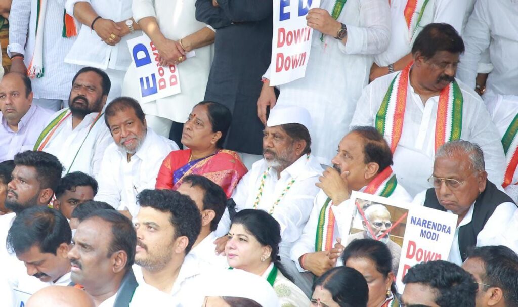 Telangana Congress leaders sitting in protest outside the Enforcement Directorate (ED) office in Hyderabad, holding placards and raising slogans.
