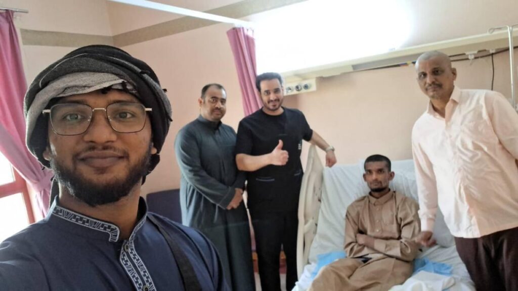 A man on a hospital bed with medical staff and relatives.