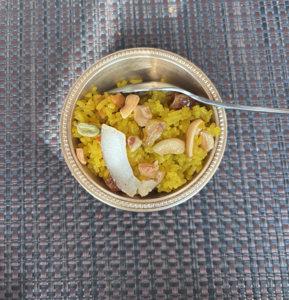 Traditional Hyderabadi chicken biryani served in a metal bowl with rice, spices, and garnishes.