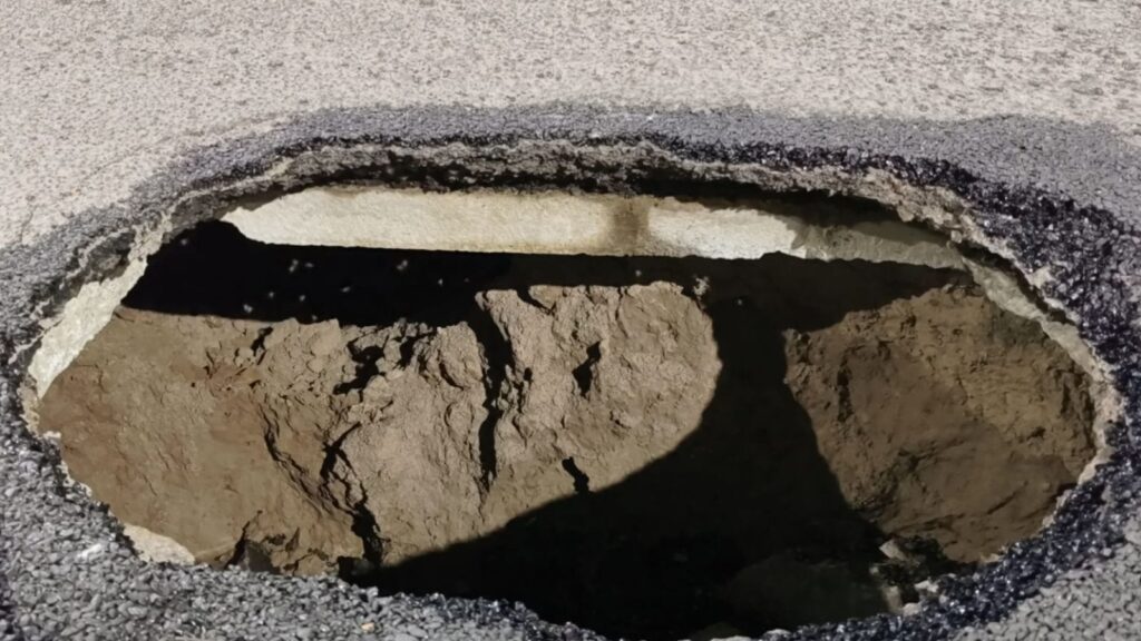 Pothole on New Malakpet Road in Hyderabad, causing traffic hazards and vehicle damage.