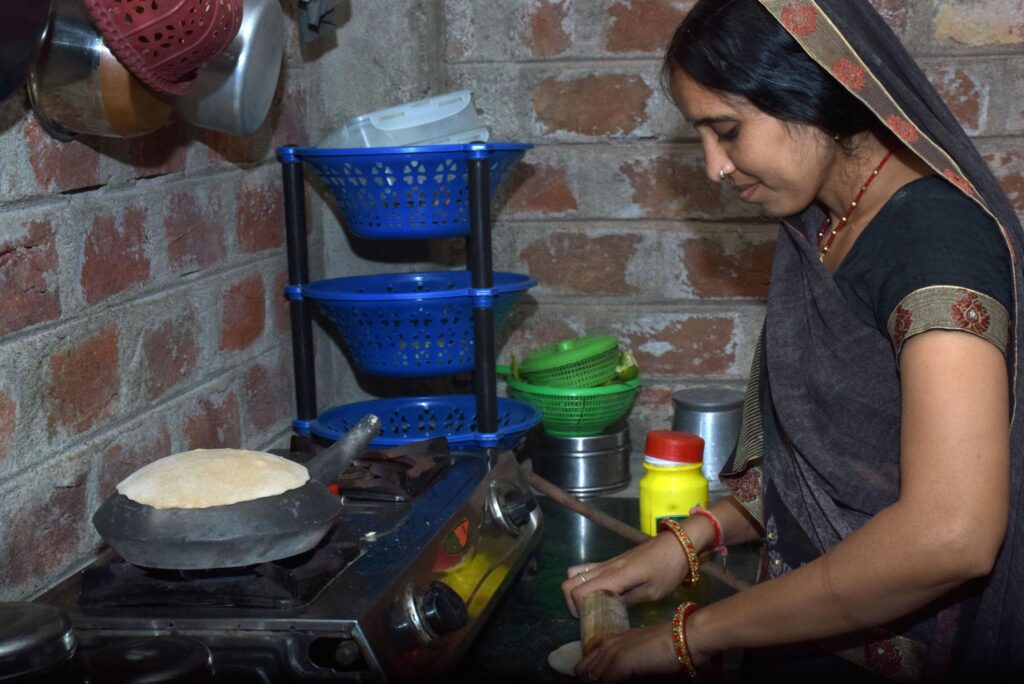 Cooking woman using LPG stove to prepare food at home.