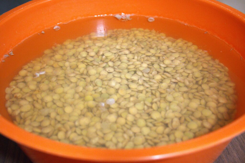 Lentils soaking in water in an orange bowl, a step to make your lentils last longer and save LPG during s.