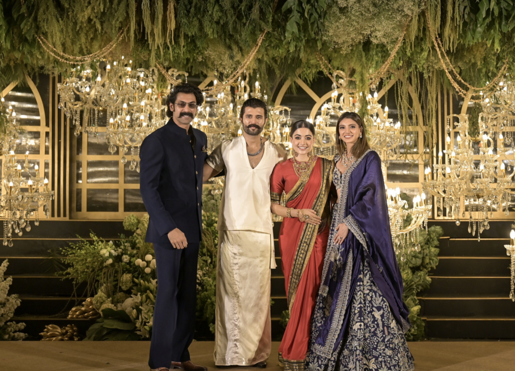 A group of four friends dressed in traditional and formal attire at a festive celebration, with elegant d.