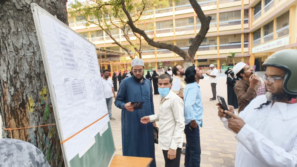 A police officer checking his phone outside an exam centre during SSC exams in Telangana.