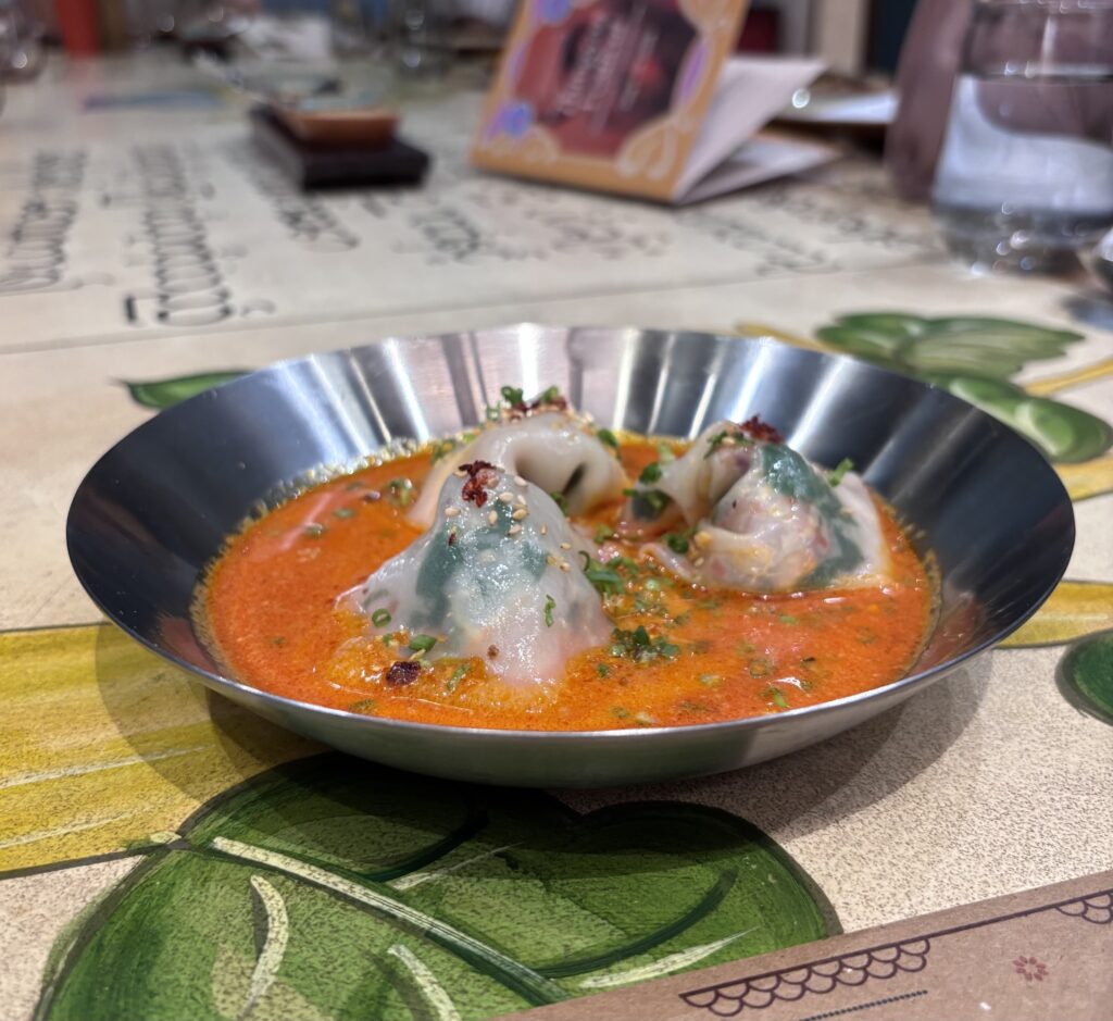 Traditional Burmese fish curry served in a metal bowl with herbs and spices, perfect for a festive feast.