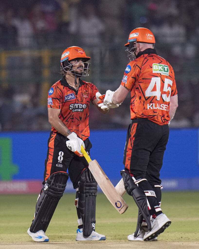 SRH cricket players in orange jerseys celebrating during IPL match.