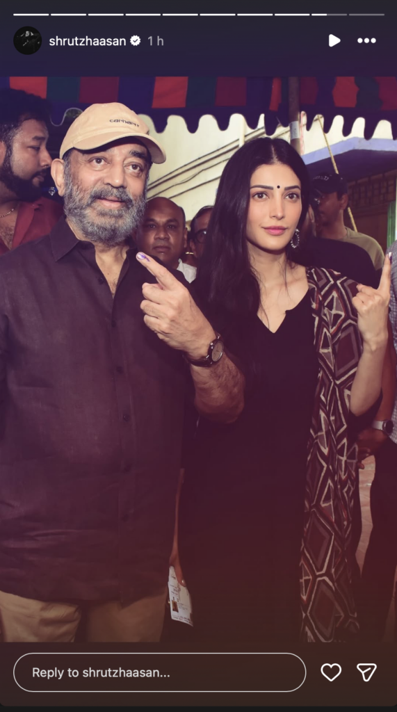 Man and woman at Siasat Daily event, posing for photo under a tent, media coverage, and crowd in backgrou.