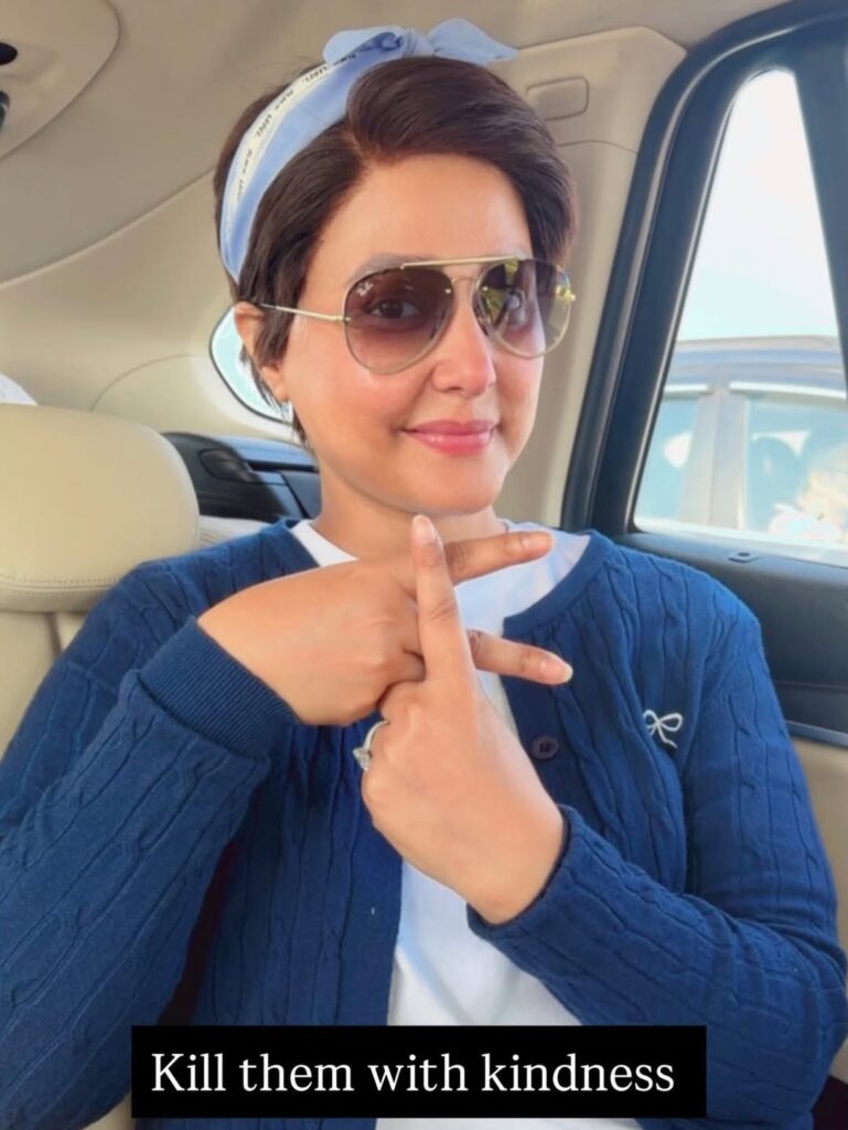 Female contestant in sunglasses making a peace sign.