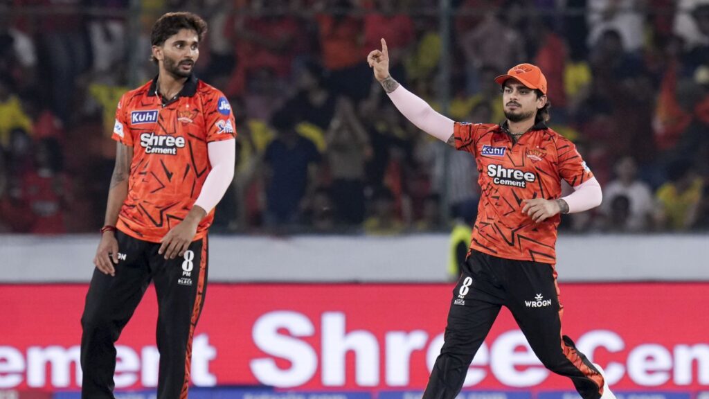 Two cricket players in red uniforms celebrating on the field during a match.
