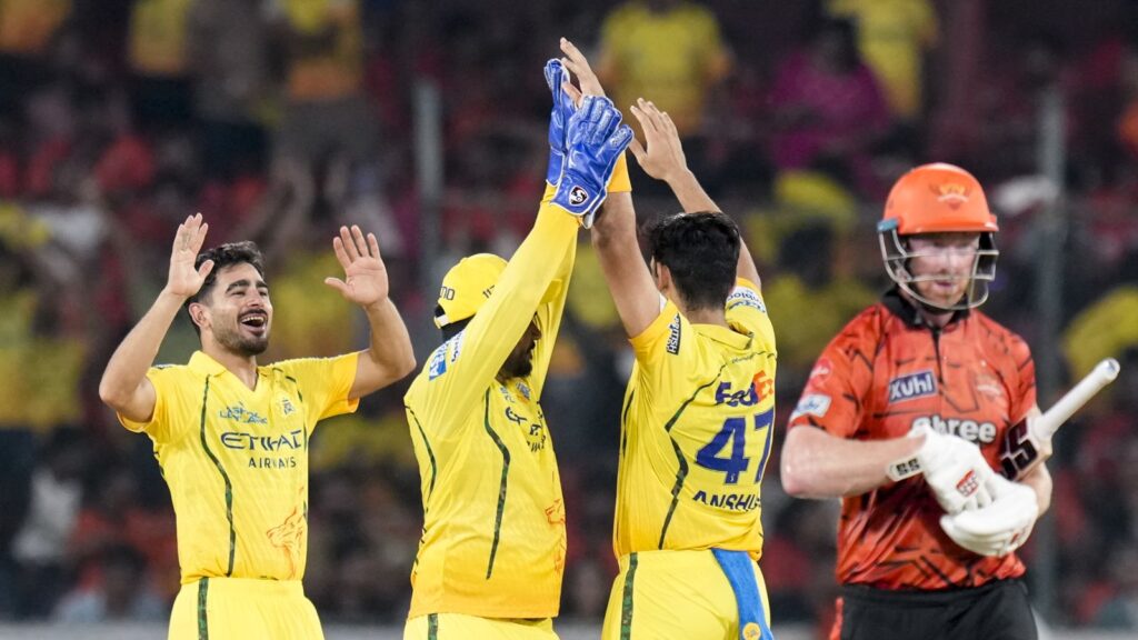 Celebrating a cricket victory with players in yellow jerseys high-fiving on the field, while the opposing.