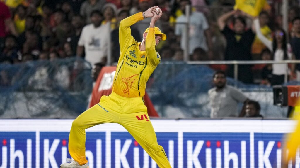 Cricket player in yellow uniform celebrating on the field during a match.