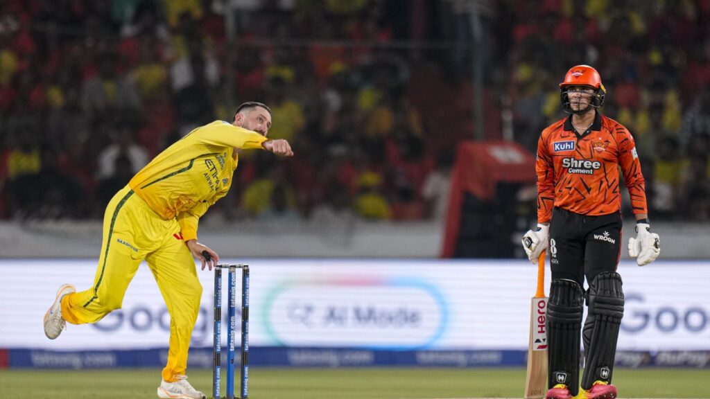 Celebrating cricket wicket, bowler in yellow uniform with teammate in stadium during match.