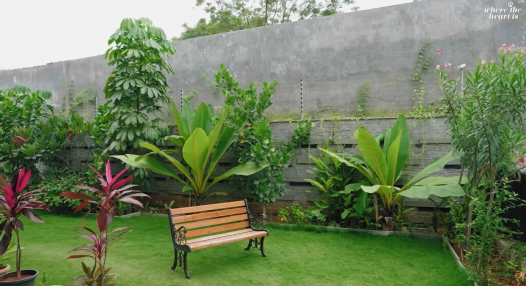 Beautiful view of a lush garden with tropical plants and a wooden bench in a private hilltop residence.