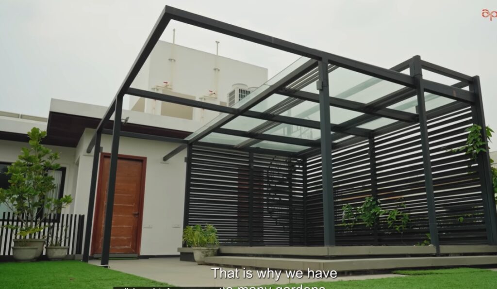 Outdoor patio with glass roof and black metal frame in Hyderabad home.