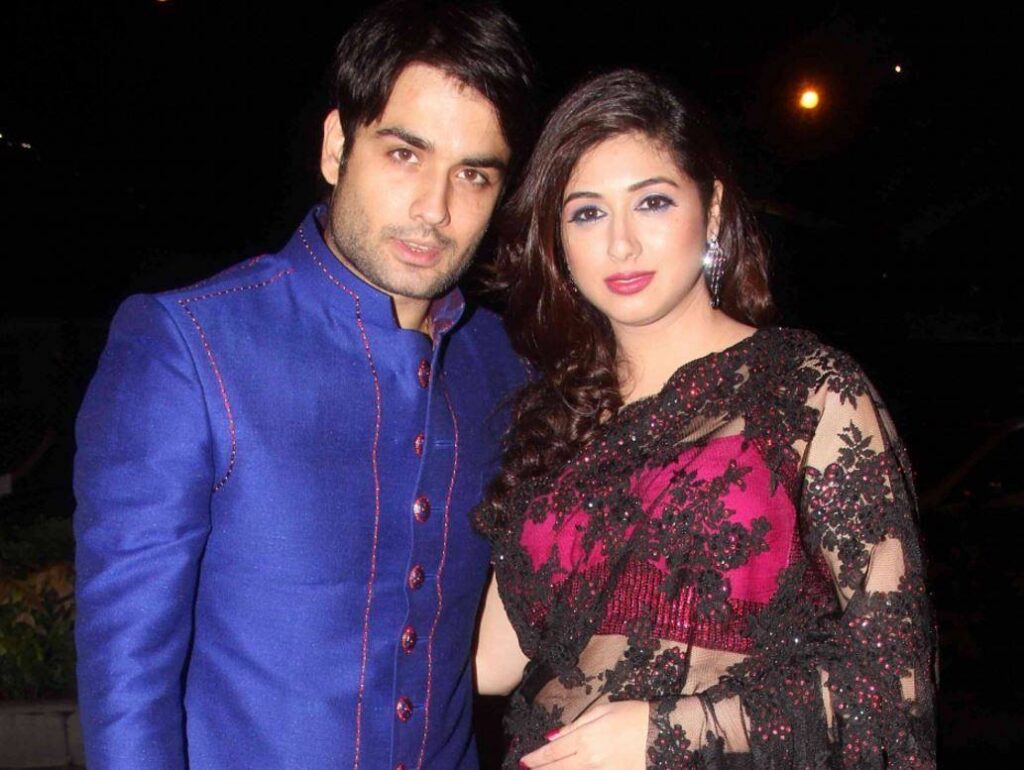 Couple dressed in elegant traditional outfits, posing outdoors during night with soft lighting, showcasin.