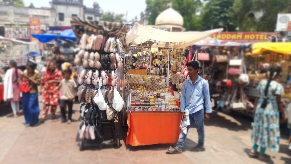Vibrant street market stall selling bags, accessories, and souvenirs in a busy outdoor shopping area.