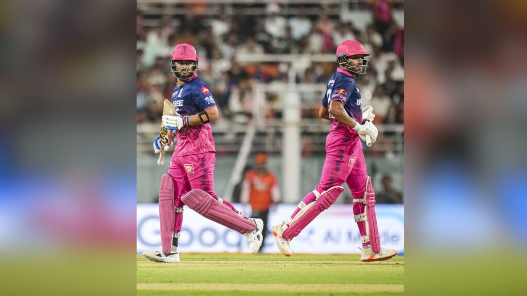 A woman cricketer in pink and blue uniform running on the field during a match.