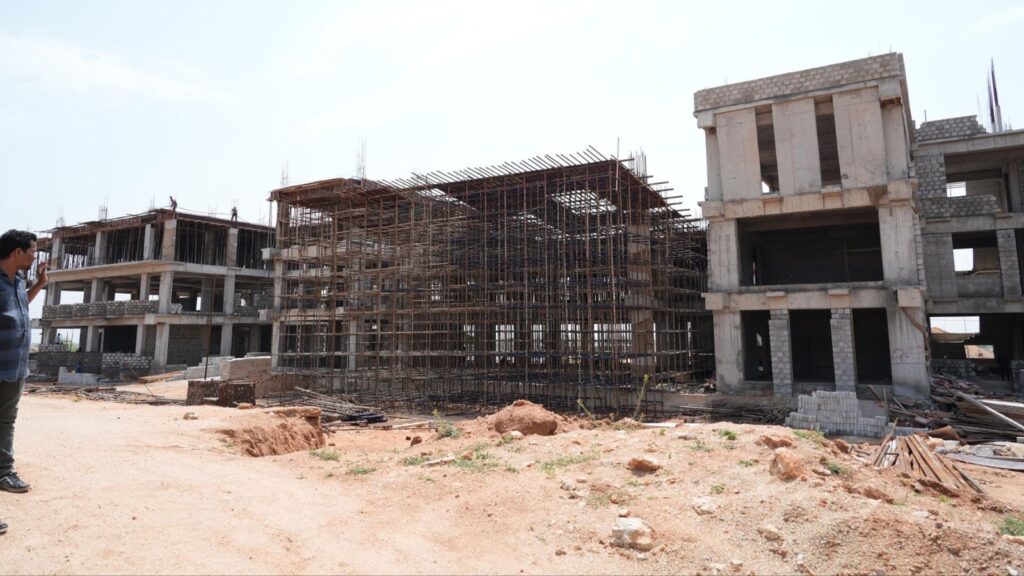 Construction site with partially built multi-storey buildings and scaffolding under a clear sky.
