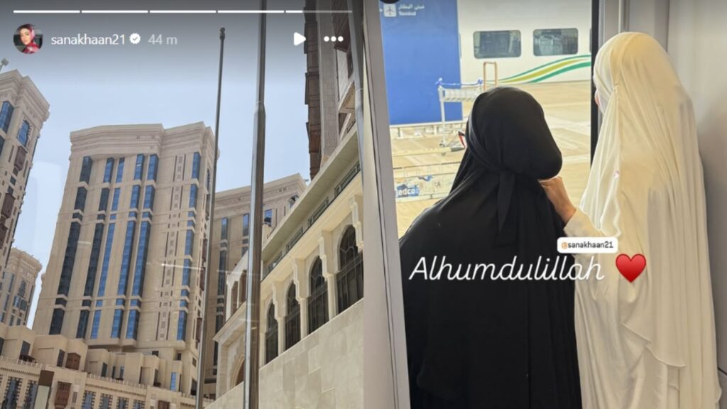 A woman in black hijab and a woman in white hijab looking at a train at a station, with a cityscape in th.