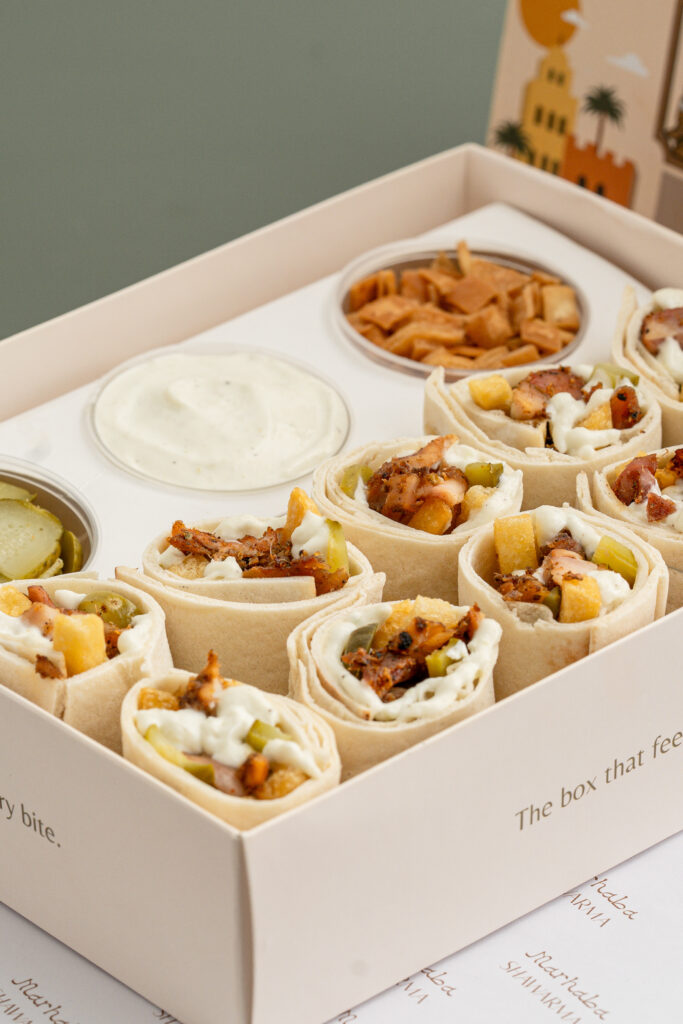 Mini chicken and vegetable wraps with dipping sauces in a white box, ready for serving.